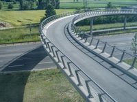 a curved road leading through a rural countryside area with highway traffic in the distance against a blue sky