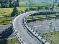 a curved road leading through a rural countryside area with highway traffic in the distance against a blue sky