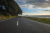 a lone highway stretches along the edge of a cliff at sunset near the ocean or water