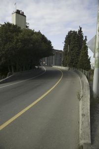 a paved street with traffic signage and building in the background in front of it on a hillside