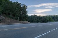 a highway with a sign and a man on his bike in the foreground, near trees