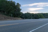 a highway with a sign and a man on his bike in the foreground, near trees