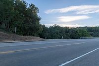 a highway with a sign and a man on his bike in the foreground, near trees