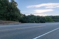 a highway with a sign and a man on his bike in the foreground, near trees