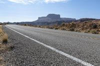 a car is driving on an empty highway through the desert, which is covered with rocks