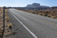 a car is driving on an empty highway through the desert, which is covered with rocks