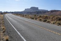 a car is driving on an empty highway through the desert, which is covered with rocks