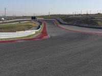 an empty track at a motorsports club with some red and white stripeing on it