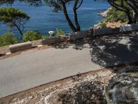 a motorcyclist riding on an empty paved road by the sea or a small island