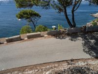 a motorcyclist riding on an empty paved road by the sea or a small island