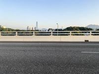 a person is riding a skateboard along an open road with some tall buildings and mountain