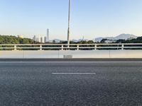 a person is riding a skateboard along an open road with some tall buildings and mountain