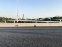 a person is riding a skateboard along an open road with some tall buildings and mountain