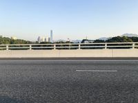 a person is riding a skateboard along an open road with some tall buildings and mountain