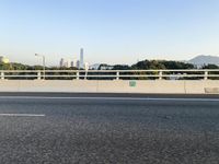 a person is riding a skateboard along an open road with some tall buildings and mountain