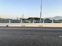 a person is riding a skateboard along an open road with some tall buildings and mountain