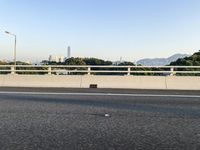 a person is riding a skateboard along an open road with some tall buildings and mountain