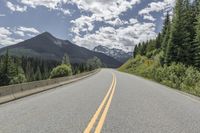 the highway is in front of a mountain and trees on both sides of it in a wide empty area