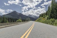 the highway is in front of a mountain and trees on both sides of it in a wide empty area