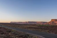 two men are riding down the highway in the middle of a big mountain range at sunset