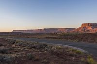 two men are riding down the highway in the middle of a big mountain range at sunset