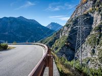 a highway with the mountains in the background with power lines on both sides and wires hanging over it