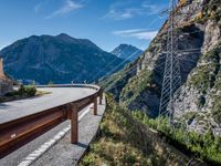 a highway with the mountains in the background with power lines on both sides and wires hanging over it