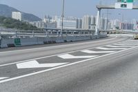 a view from an overpass of highway with two white arrows on the roadway and a few buildings in the background