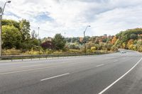 a highway with signs on both sides in front of an autumn landscape and a blue sky with white clouds