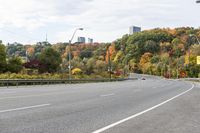 a highway with signs on both sides in front of an autumn landscape and a blue sky with white clouds