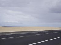 there is a highway with sand dunes in the background in this photo, the road goes to the right