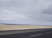 there is a highway with sand dunes in the background in this photo, the road goes to the right