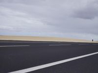 there is a highway with sand dunes in the background in this photo, the road goes to the right