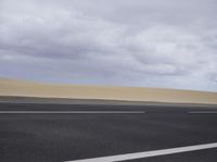 there is a highway with sand dunes in the background in this photo, the road goes to the right