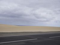 there is a highway with sand dunes in the background in this photo, the road goes to the right