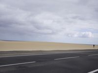 there is a highway with sand dunes in the background in this photo, the road goes to the right