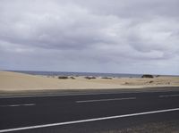 there is a highway with sand dunes in the background in this photo, the road goes to the right