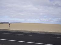 there is a highway with sand dunes in the background in this photo, the road goes to the right