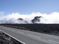 the highway winds its way through a vast field of lava and rocks in the distance, clouds billowing