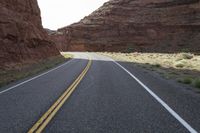 a person riding a motorcycle along a narrow road through rocks and sand cliffs a grassy area on both sides