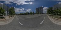 a 360 - angle photograph of the highway through the city on a cloudy day, with high rise buildings in the distance