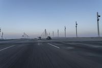 a highway with traffic on it and construction cranes in the background during the day and dusk