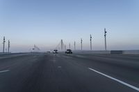 a highway with traffic on it and construction cranes in the background during the day and dusk