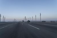 a highway with traffic on it and construction cranes in the background during the day and dusk