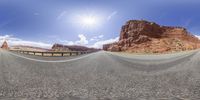 a photo taken looking into a fish - eye lens at a road next to the red rocks