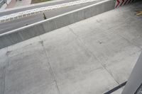 a person riding a skateboard down a ramp on cement walkway next to a street