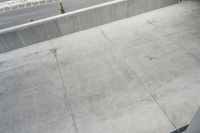 a person riding a skateboard down a ramp on cement walkway next to a street