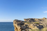 a person is hiking on a cliff above the water with a sky background, at a beach