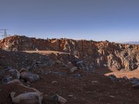 the hikeer is walking along a rocky mountain landscape in the sun set, near to an orange rock cliff and a vast view