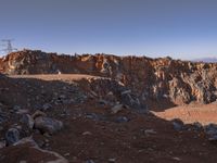 the hikeer is walking along a rocky mountain landscape in the sun set, near to an orange rock cliff and a vast view